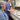 Two people working at a printing press with printed materials on a table.