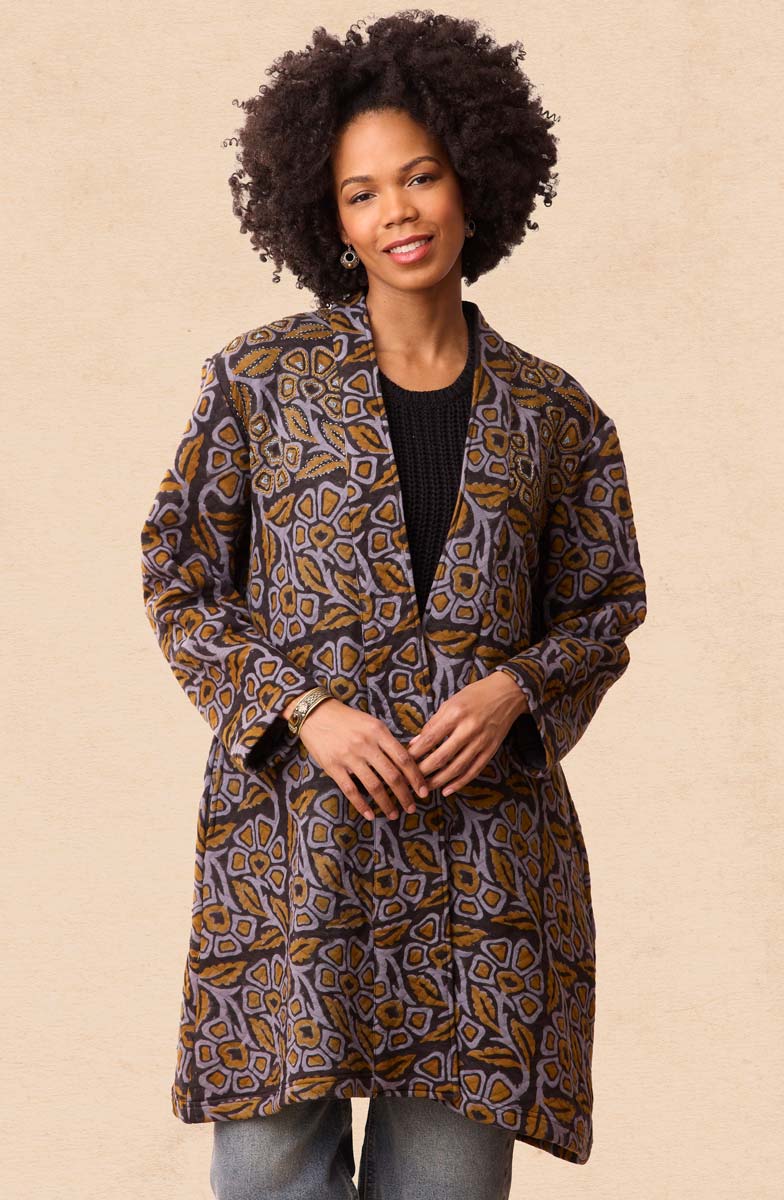 Woman wearing a patterned coat against a beige background