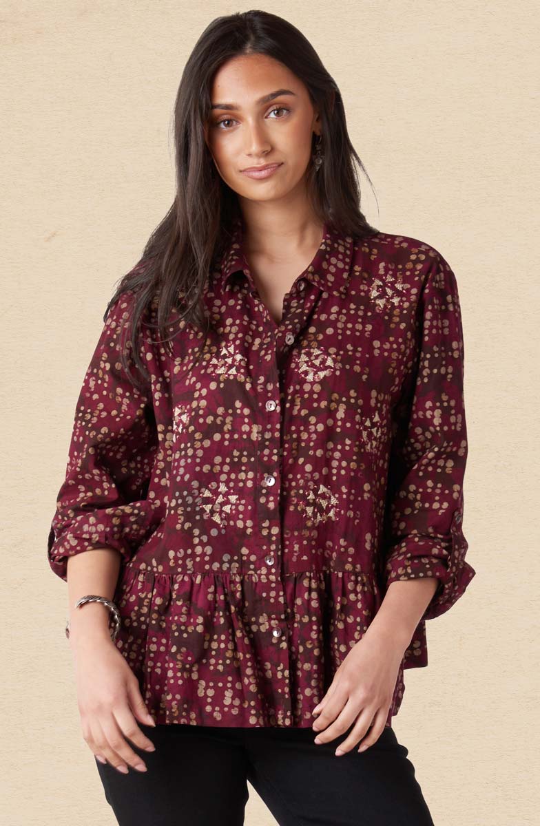 Woman wearing a patterned blouse against a beige background