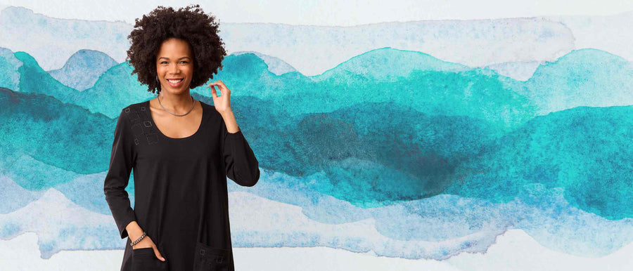 Woman in black outfit standing against a blue and white abstract background