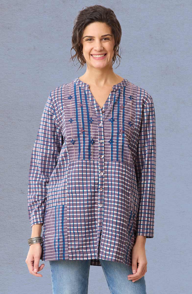 Woman wearing a plaid shirt with blue accents against a gray background