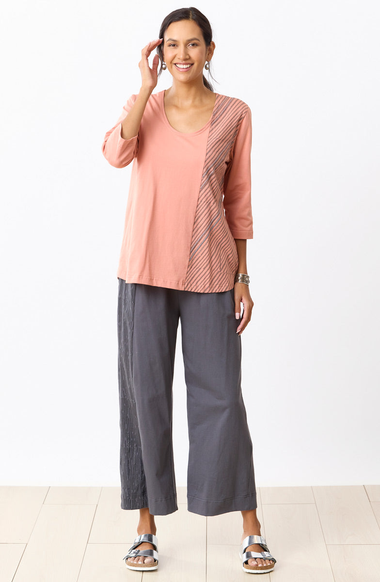 Woman wearing a pink top and gray pants on a white background