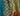 A close-up of a woodblock printed fabric showing three distinct vertical panels with different designs: a teal wavy pattern, a yellow and teal geometric maze pattern with brown buttons, and a red and orange patterned border.